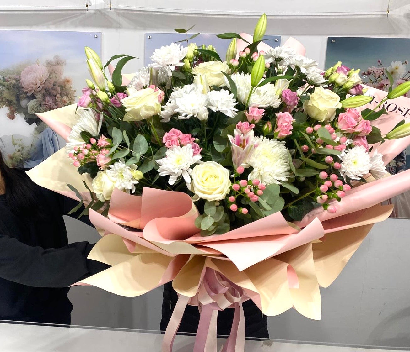 Bouquet of flowers with pink and yellow ribbons held by a person.