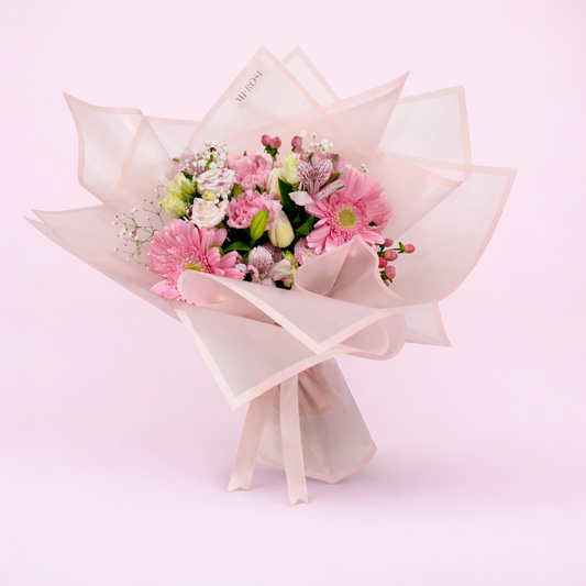 Bouquet of pink flowers wrapped in light pink paper on a light pink background