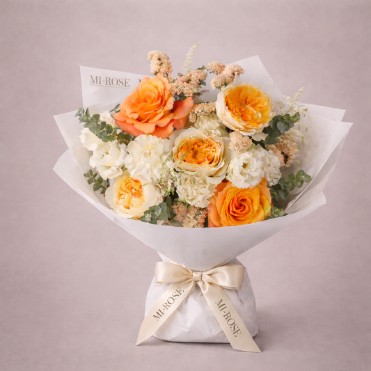 Bouquet of orange and white flowers with a 'MI-ROSE' ribbon on a light gray background