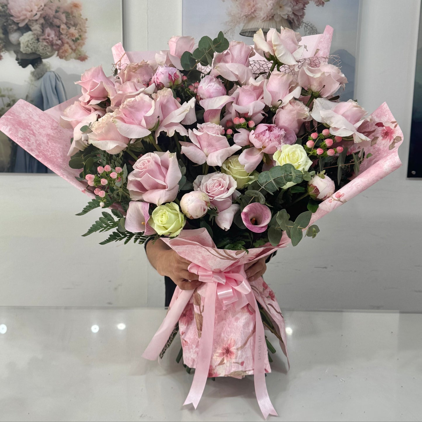 Bouquet of pink and green flowers with a decorative pink ribbon on a white surface.