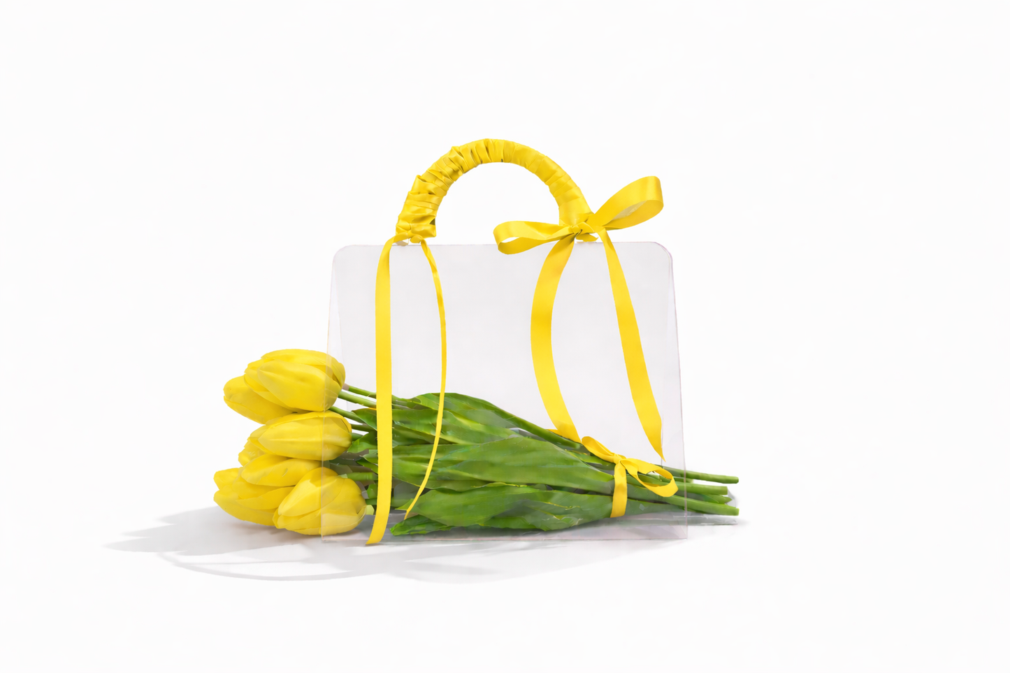 White gift box with yellow ribbon and yellow tulips on a white background